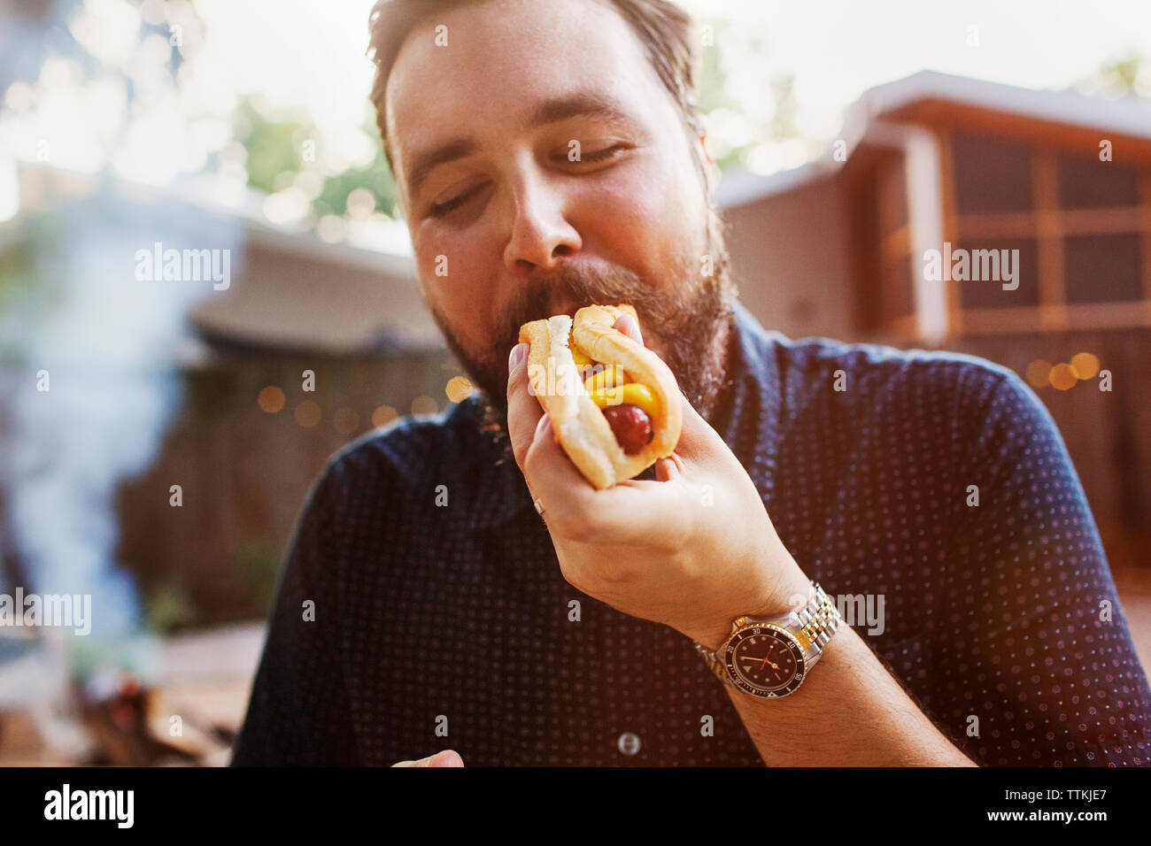 Mann essen Hot Dog im Hof Stockfoto