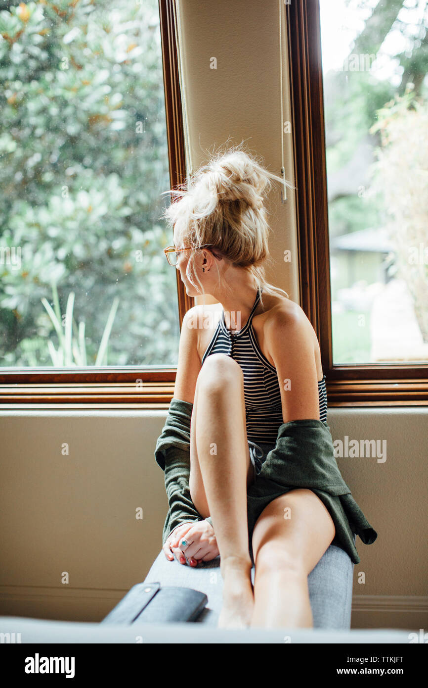 Frau weg, während auf dem Sitz von Fenster zu Hause sitzen Stockfoto Frau weg, während auf dem Sitz von Fenster zu Hause sitzen Stockfoto
