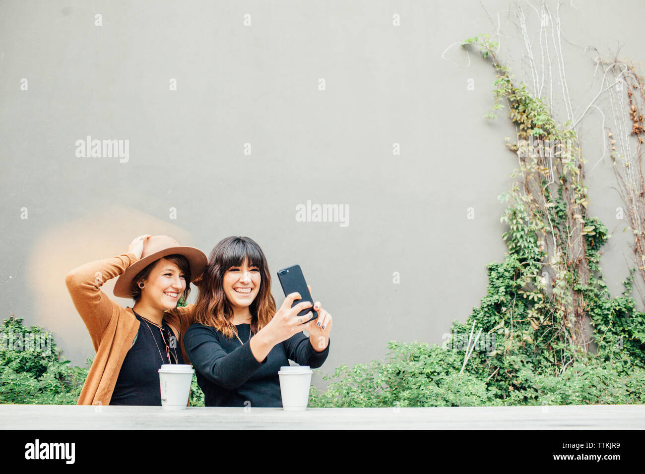 Gerne weibliche Freunde unter selfie beim Sitzen am Tisch gegen die Wand Stockfoto