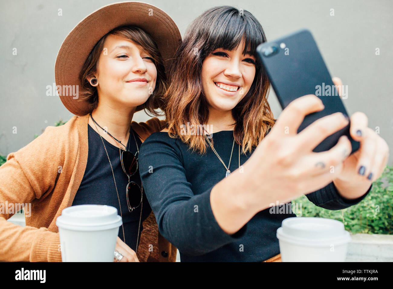 Lächelnd weibliche Freunde unter selfie bei Tisch sitzen Stockfoto