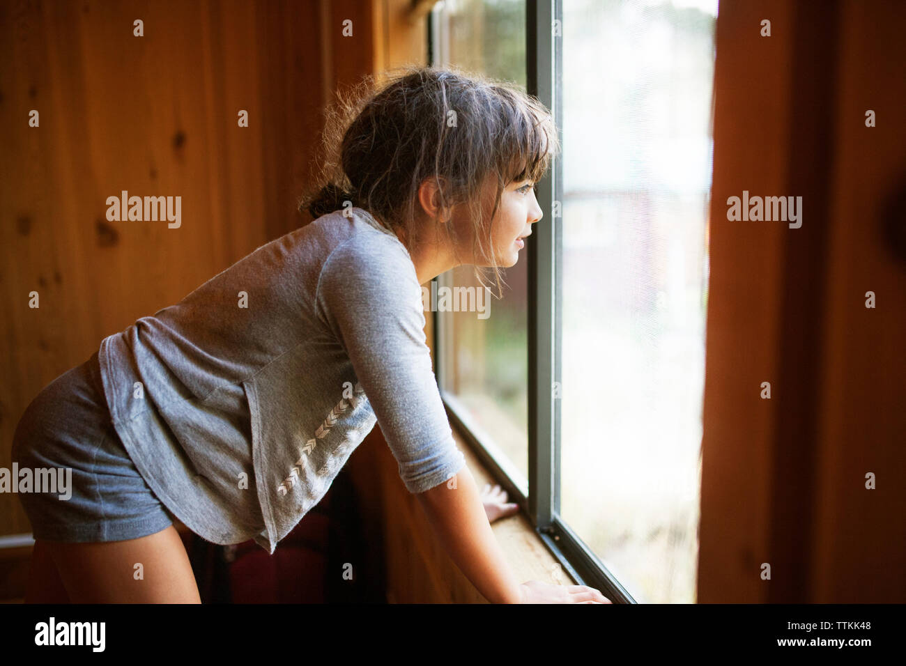 Seitliche Sicht auf Mädchen mit Blick durch das Fenster Stockfoto