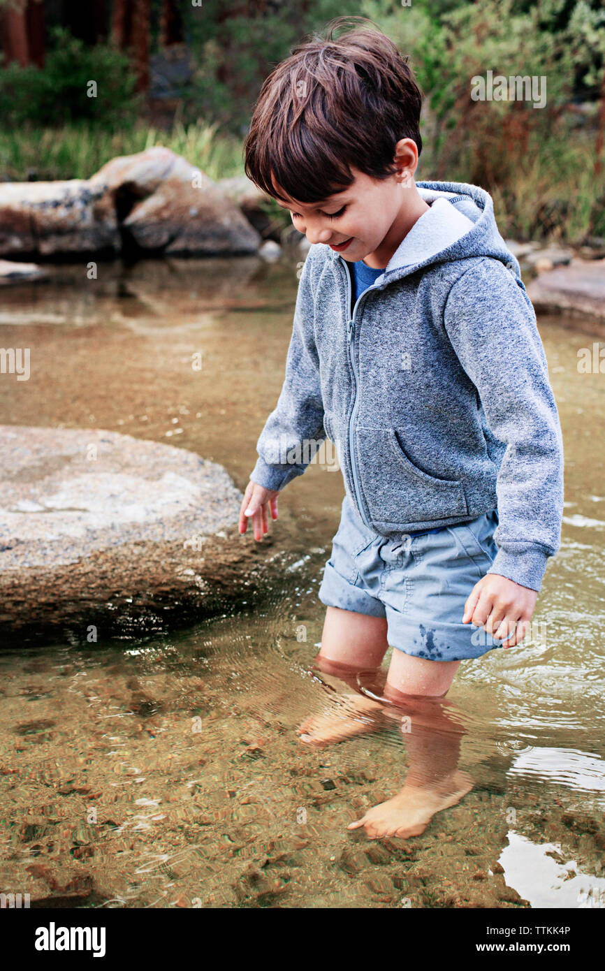 Happy Boy standing in Wasser bei Stream Stockfoto