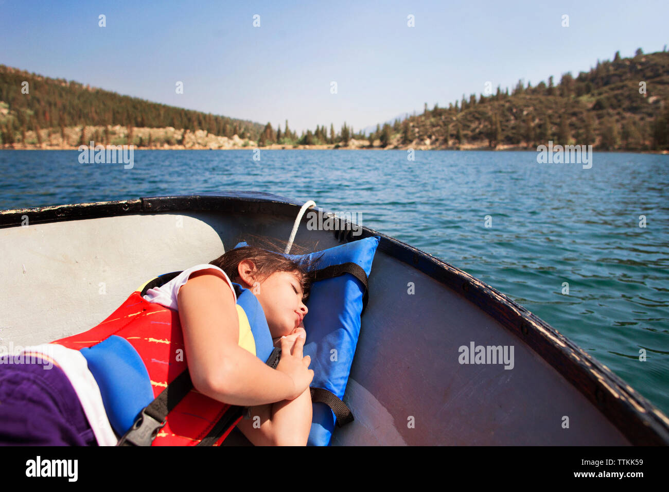 Mädchen mit Schwimmweste liegen auf dem Boot in See Stockfoto