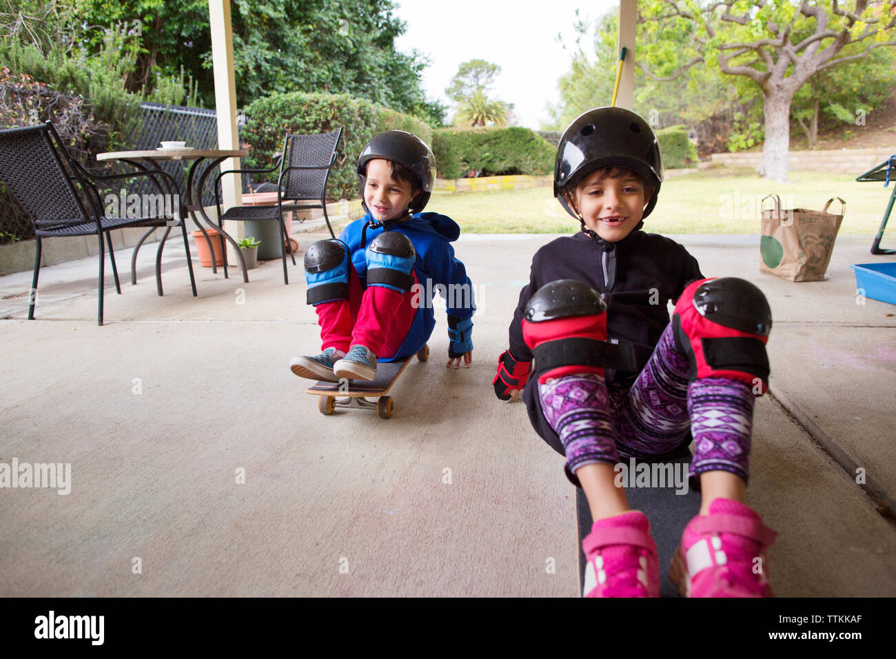 Gerne Geschwister auf Skateboards im Hof sitzen Stockfoto