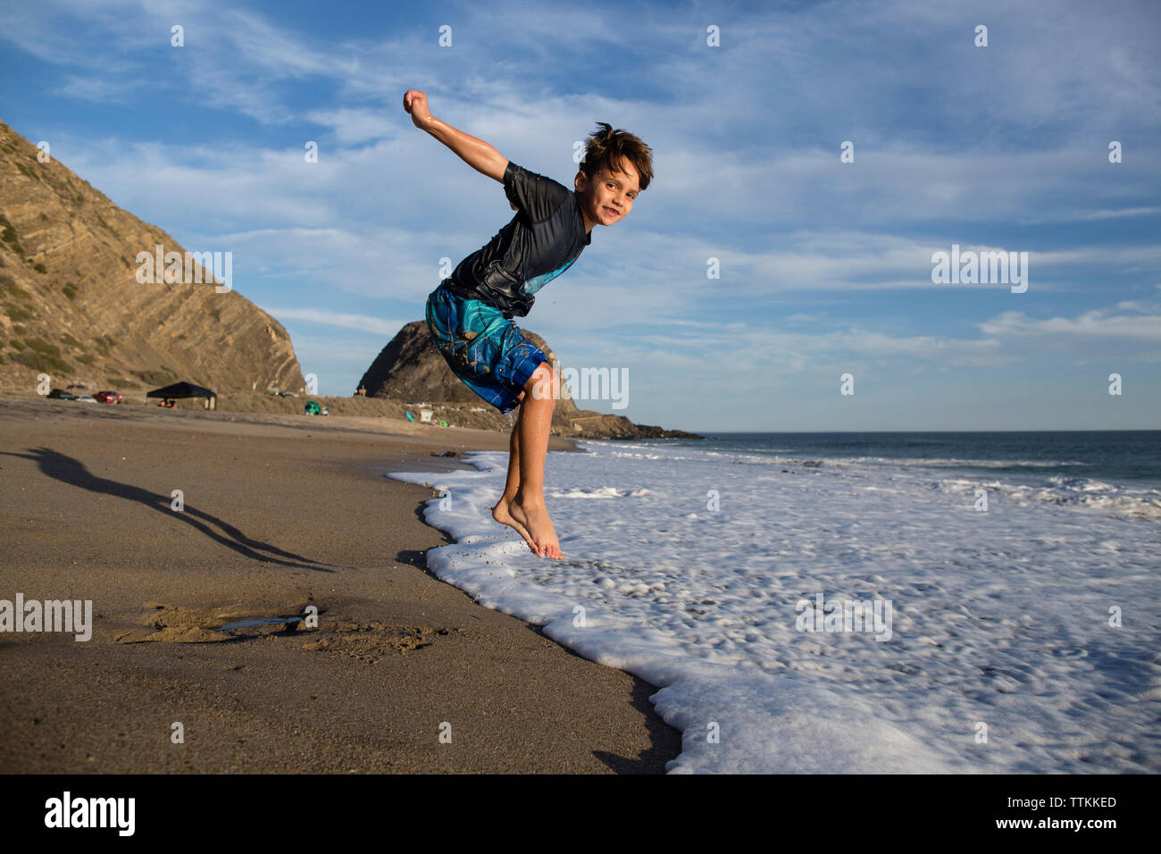 Portrait von boy Jumping in der Brandung am Strand gegen Sky Stockfoto