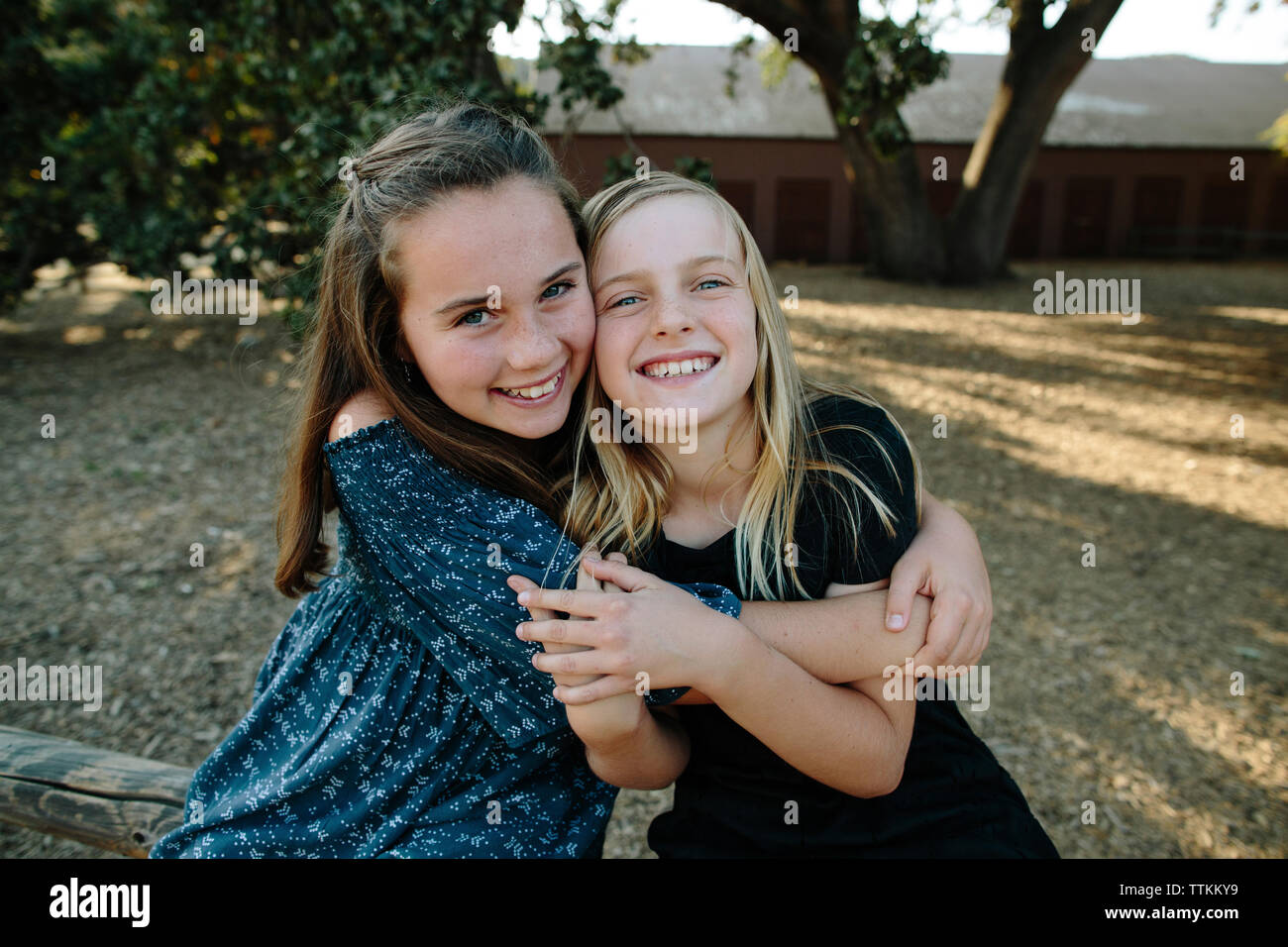 Portrait von fröhlichen Schwestern umarmen am Bauernhof Stockfoto