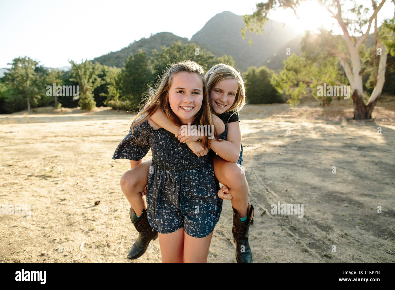 Portrait von fröhlich verspielten Mädchen huckepack Schwester am Bauernhof Stockfoto