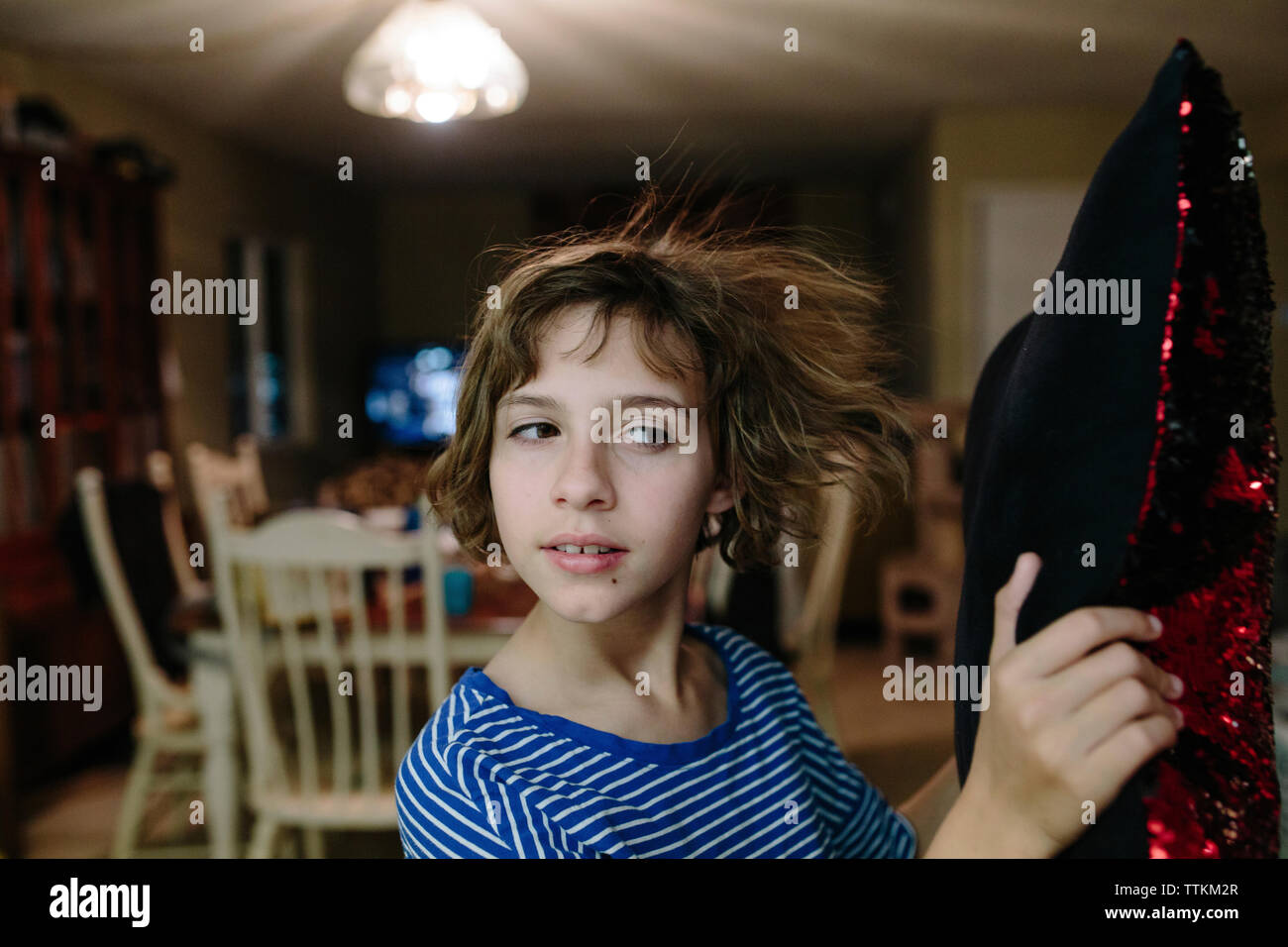 Nahaufnahme der niedliche Mädchen mit kurzen Haaren holding Kissen während zu Hause stehend Stockfoto