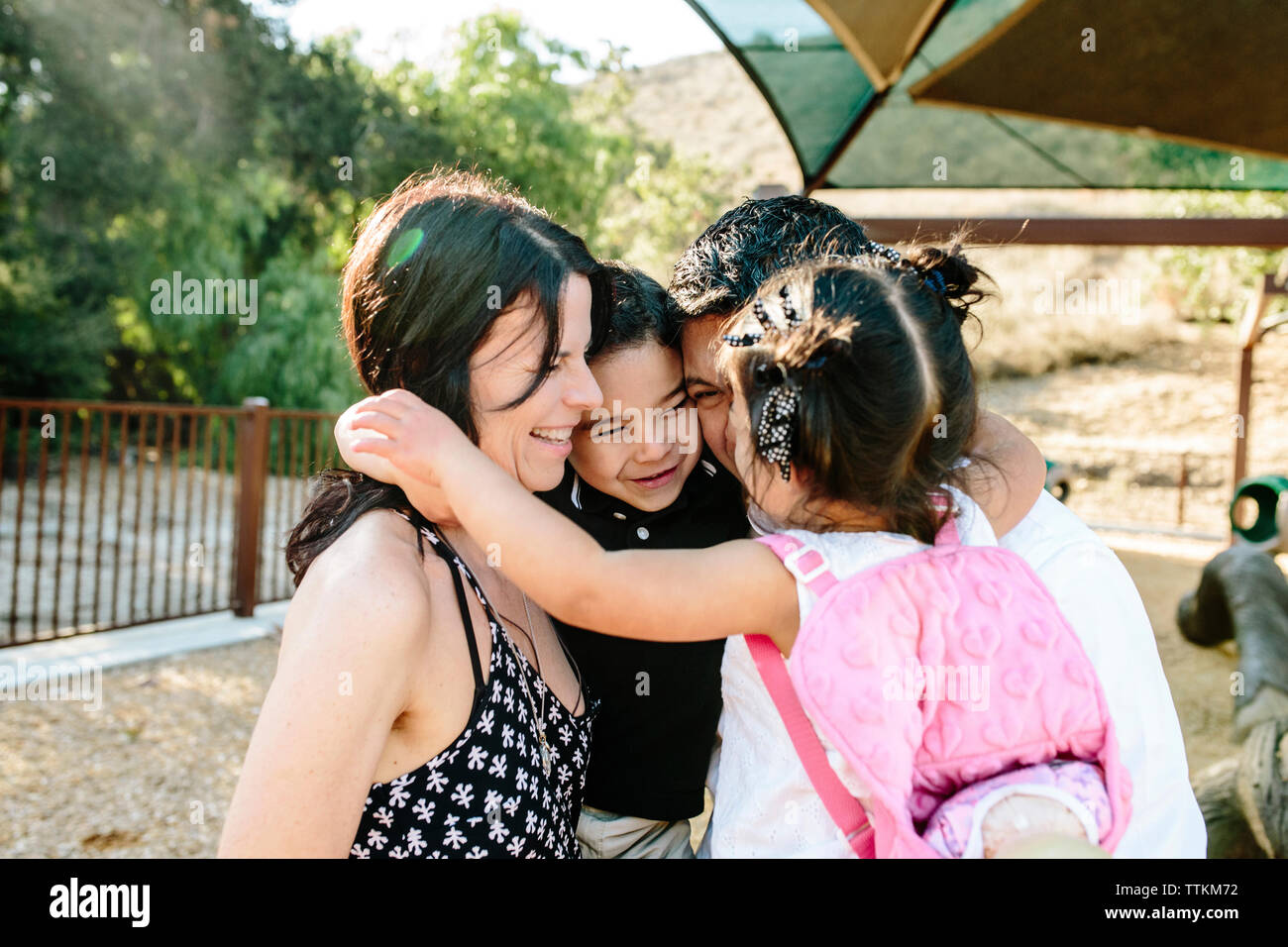 Glücklich, multi-ethnischen Eltern Kinder umarmt, während in PARK-Stellung Stockfoto