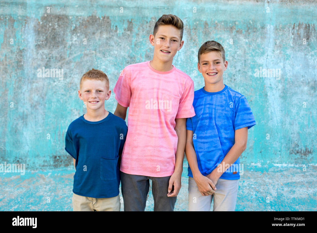 Drei Brüder Lächeln für die Kamera mit einem blauen Hintergrund Stockfoto