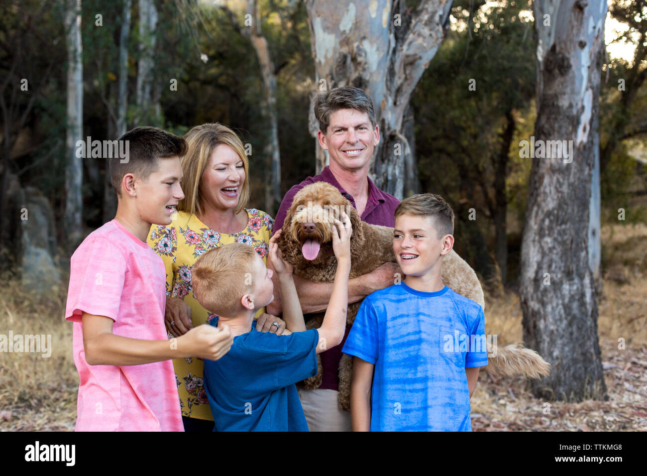 Happy Labradoodle in den Armen des Vaters, während Söhne und Frau Watch Stockfoto