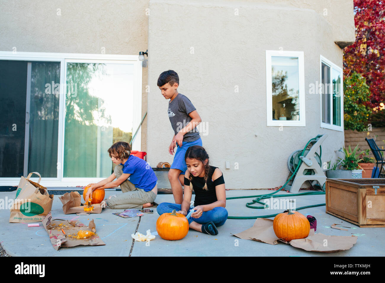 Drei Kinder schnitzen ihre Kürbisse außerhalb Stockfoto
