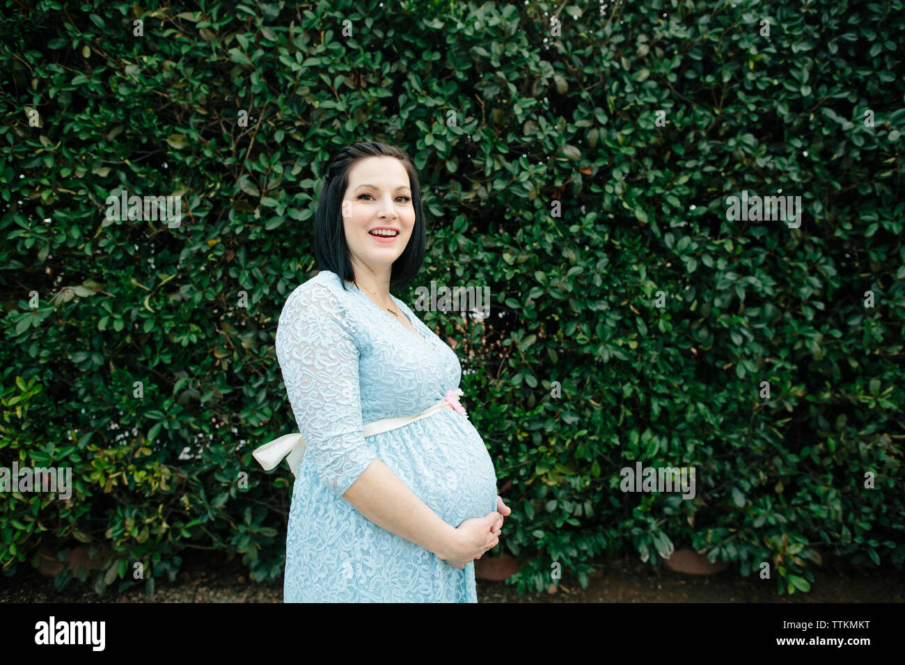 Eine schwangere Frau lacht beim Stehen für ein Portrait Stockfoto