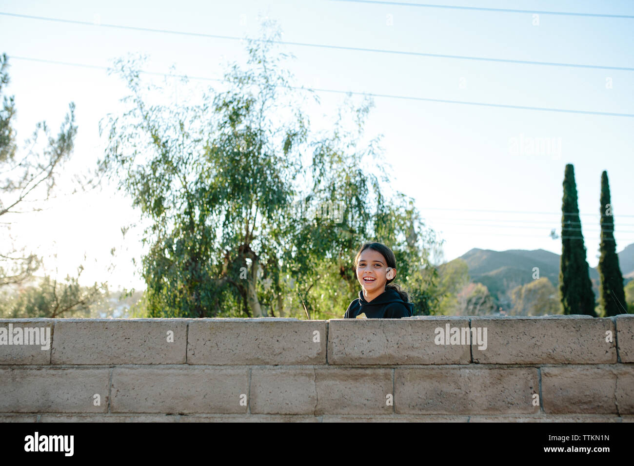 Mädchen hinter einer Wand lacht in die Kamera Stockfoto