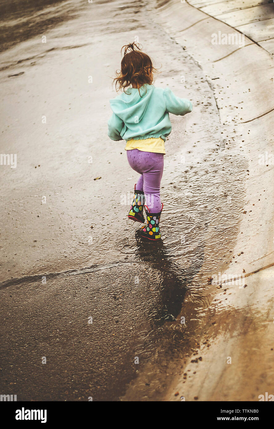 Ansicht der Rückseite des Mädchen gehen auf nassen Straßen Stockfoto