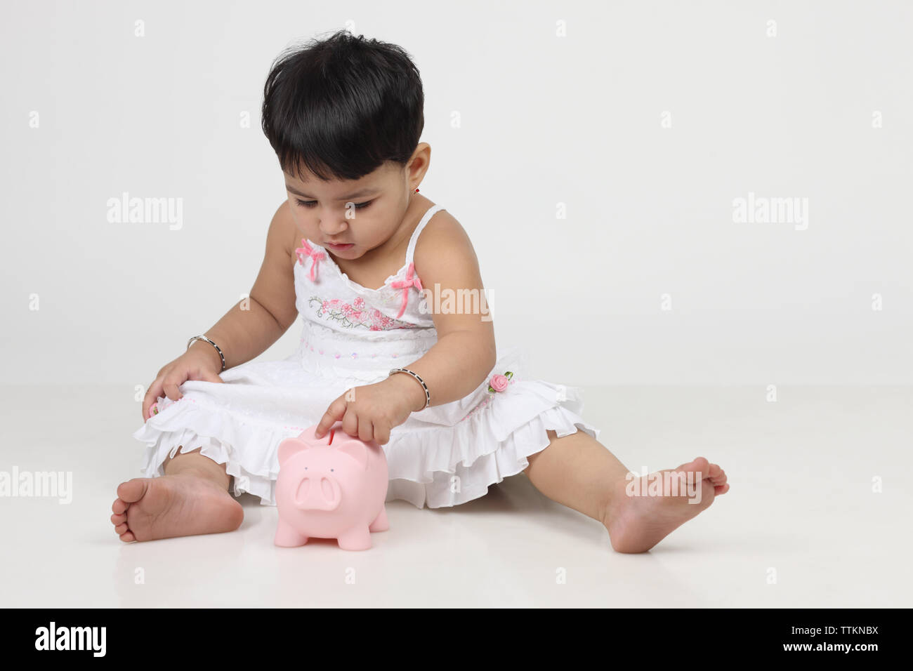 Indische Baby Mädchen spielen mit einem Sparschwein Stockfoto