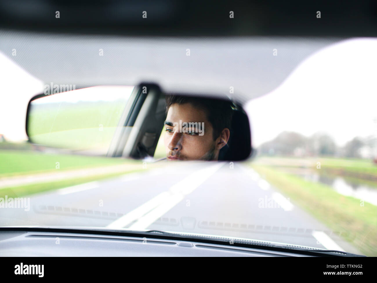 Reflexion des Menschen im Rückspiegel des Autos auf der Straße Stockfoto