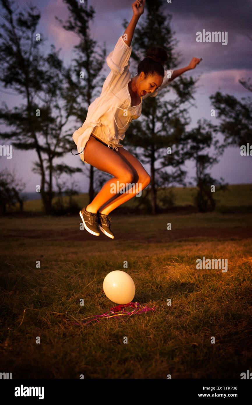 Aufgeregt Teenager platzen Ballon auf dem Feld in der Dämmerung Stockfoto