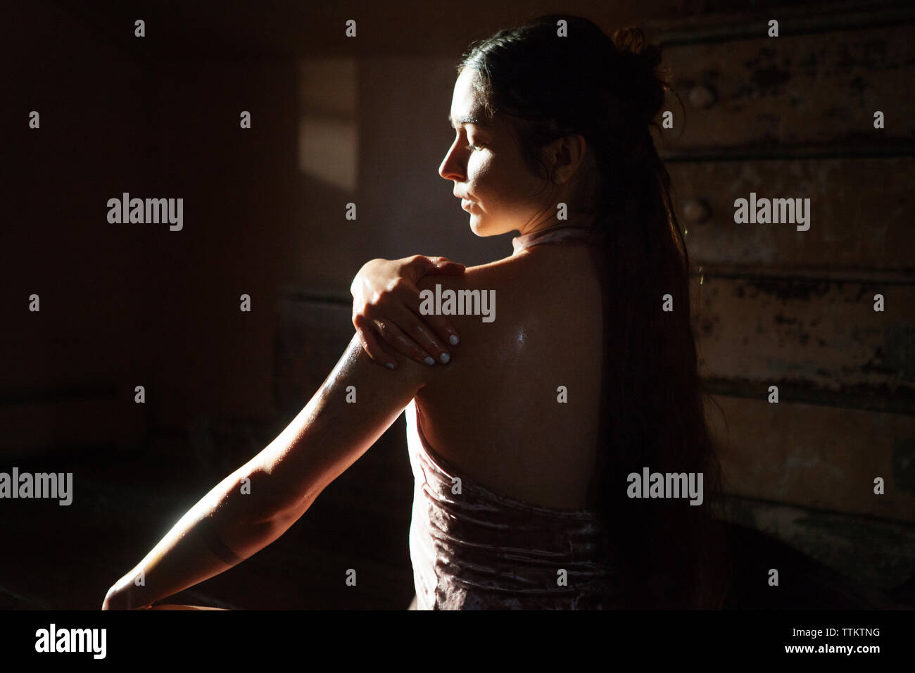 Ansicht der Rückseite Frau mit unter Druck stehendem Öl zu Körper in der Dunkelkammer zu Hause Stockfoto