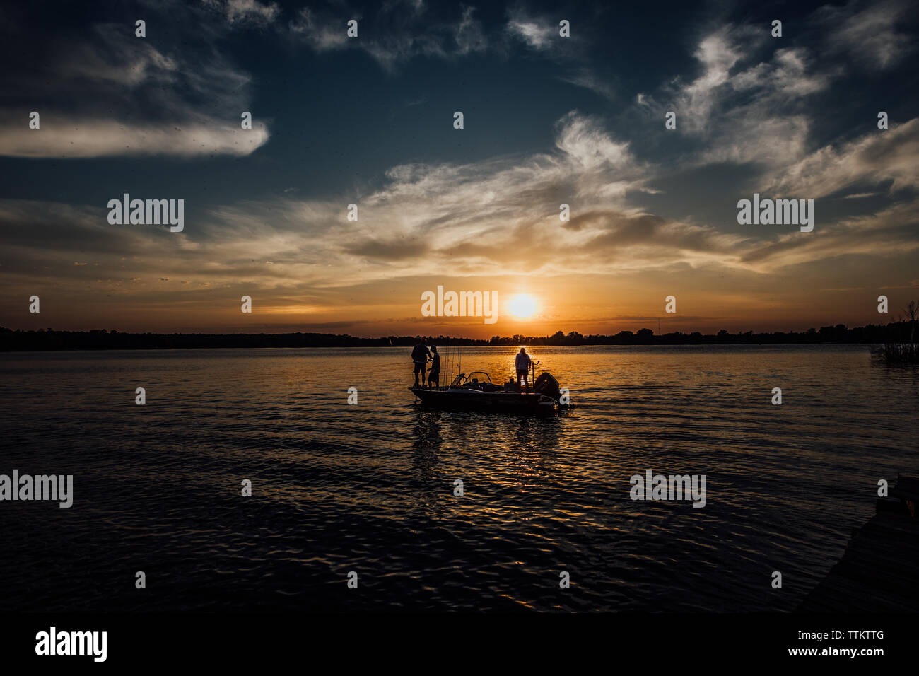 Familie Angeln auf einem Schiff bei Sonnenuntergang auf einem Wisconsin See im Sommer Stockfoto
