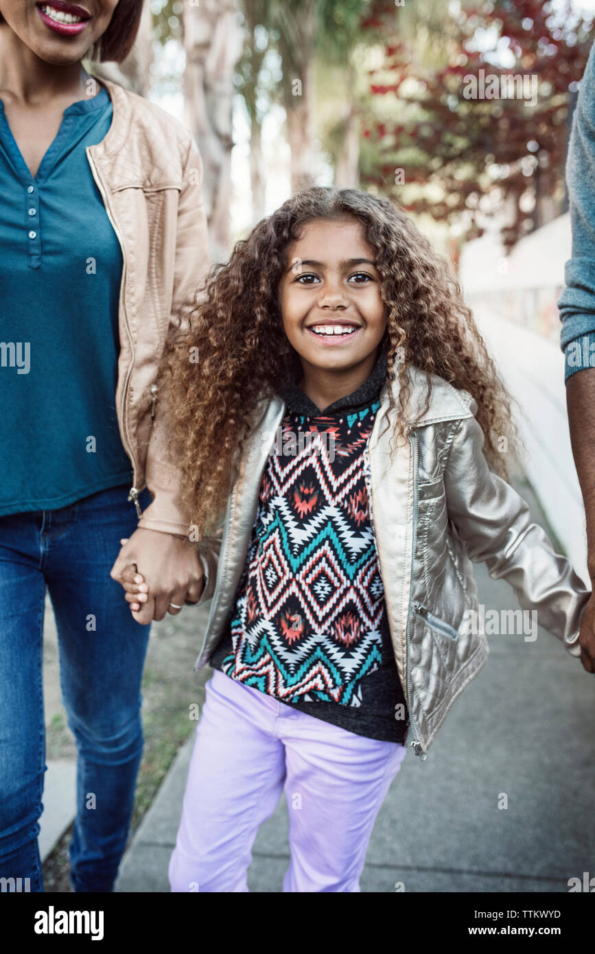 Portrait von glücklichen Mädchen gehen mit Eltern auf Bürgersteig Stockfoto