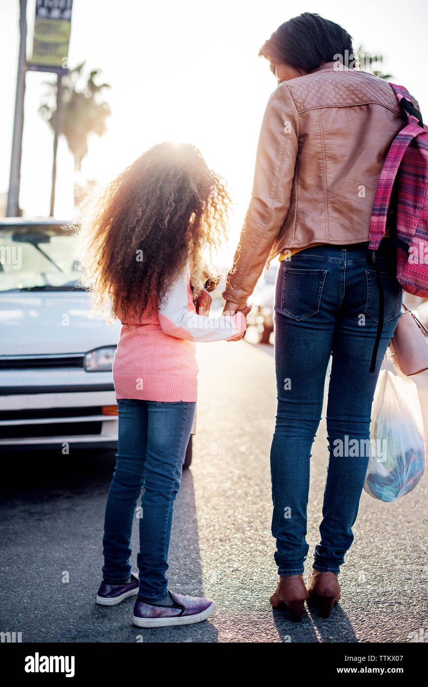 Hintere Ansicht von Mutter und Tochter halten sich an den Händen und stehen auf dem Bürgersteig Stockfoto