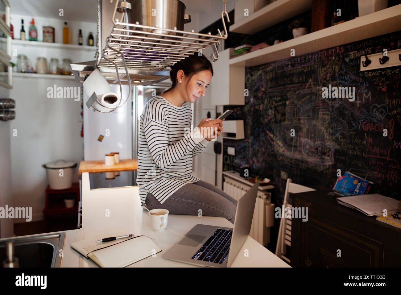 Frau Text Messaging, beim Sitzen am Tisch zu Hause Stockfoto