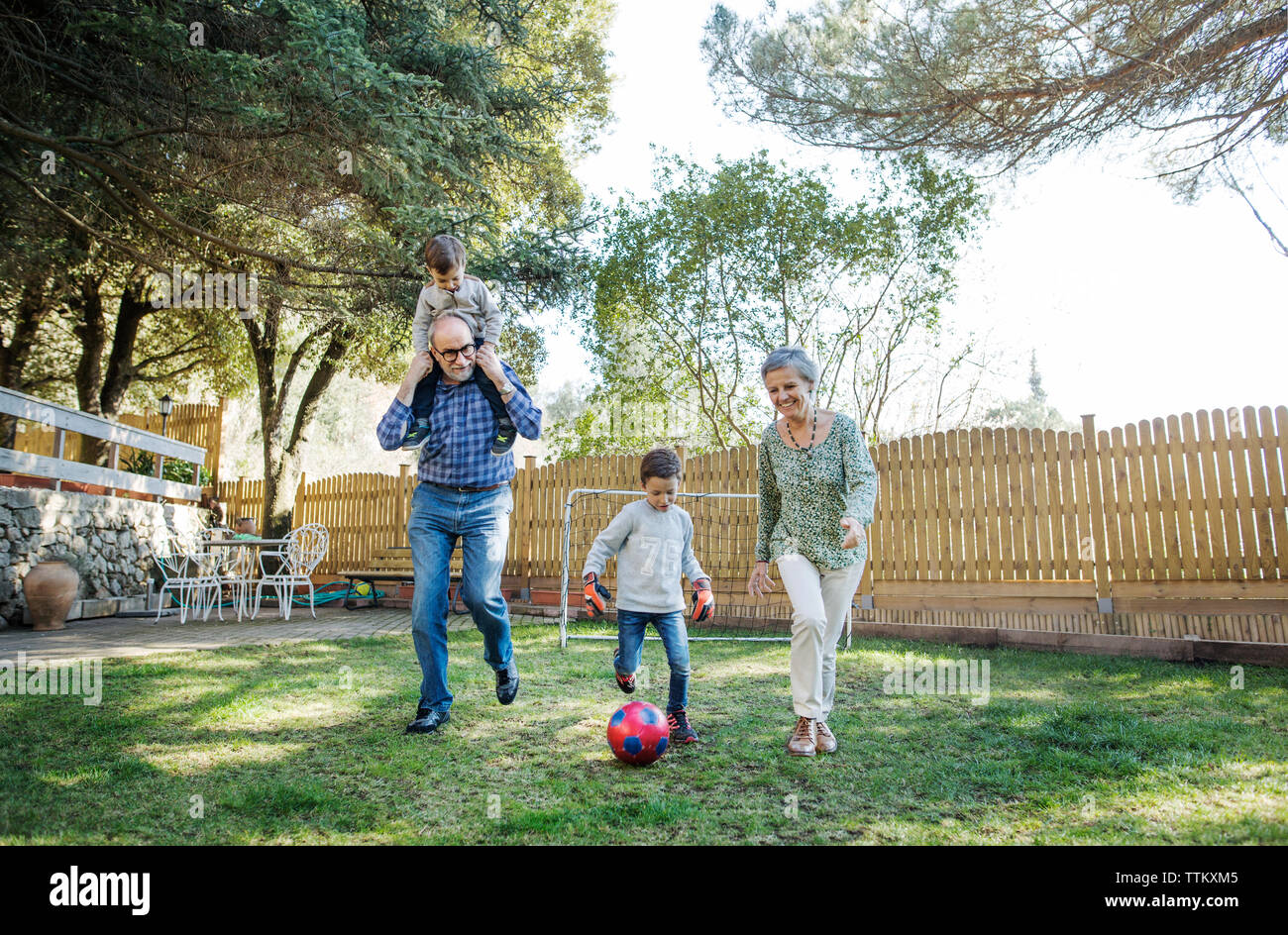 Volle Länge von Großeltern und Enkeln Fußball spielen im Hof Stockfoto