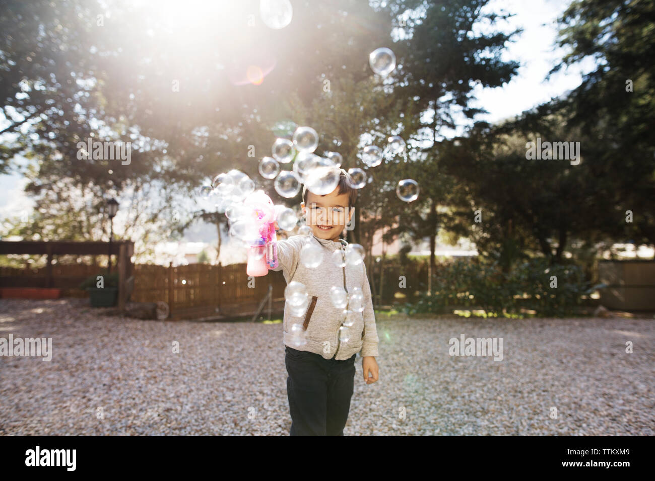 Fröhliche Junge spielt mit Bubble Gun im Hof Stockfoto