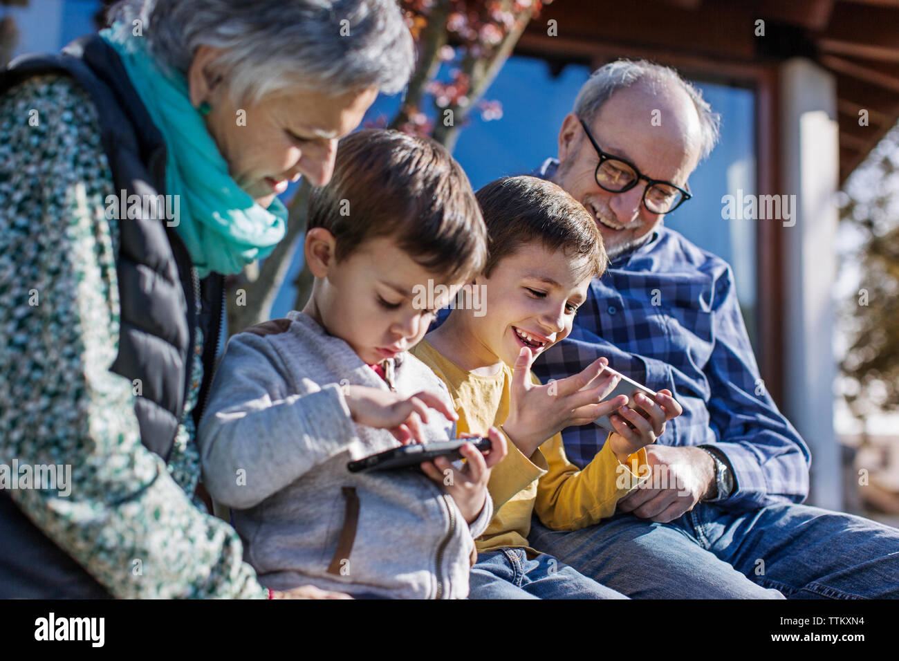 Glückliche Großeltern und Enkel mit Smartphones im Park Stockfoto