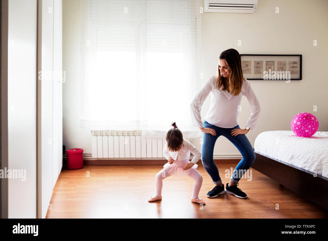 Lächelnde Mutter nachahmen Mädchen, Ballett Tanz im Schlafzimmer Stockfoto