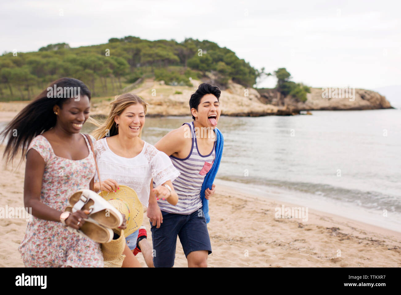 Fröhliche Freunde laufen am Strand während der Ferien Stockfoto
