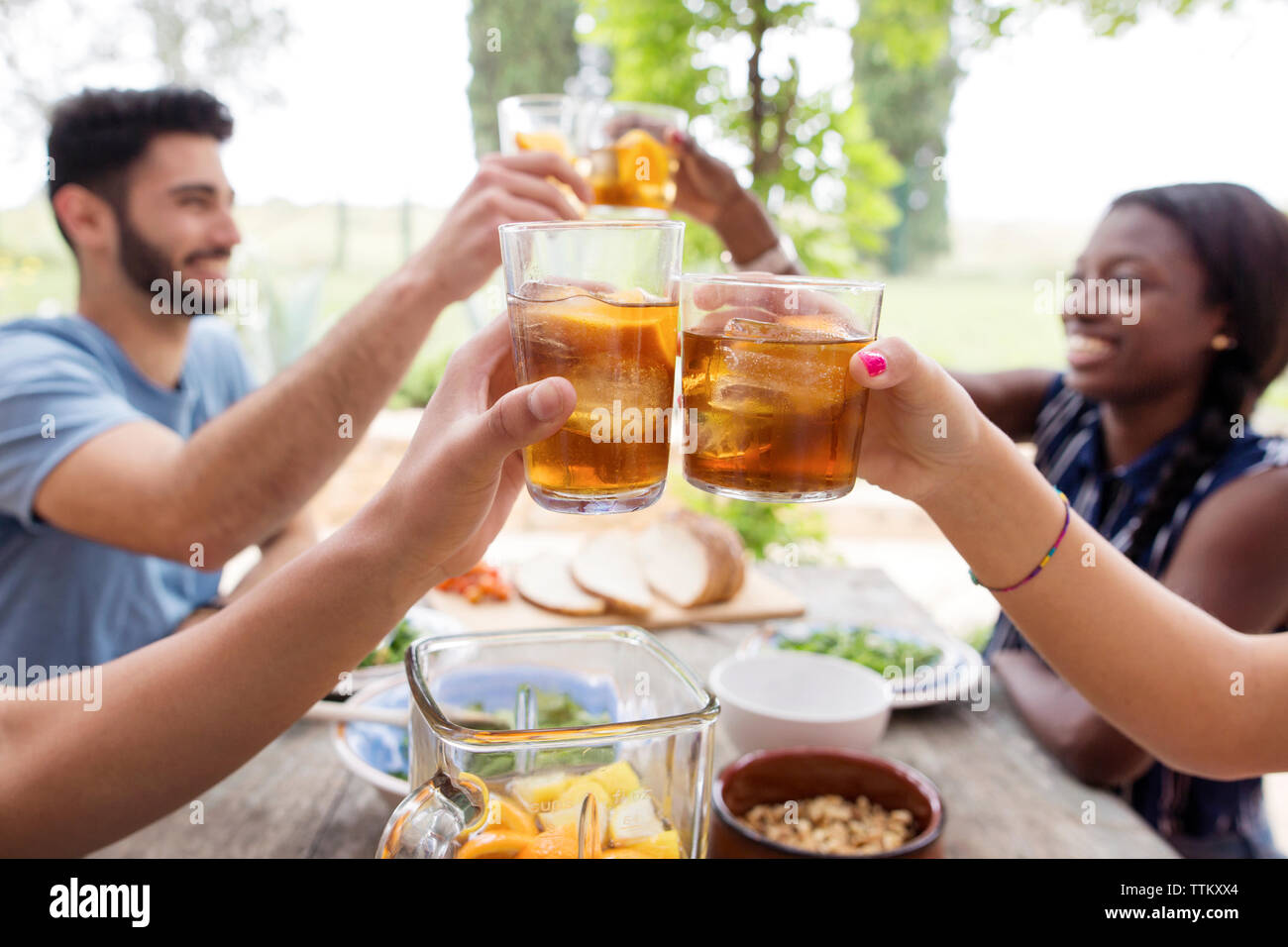 Freunde toasten Eistee Gläsern am Tisch im Freien Stockfoto