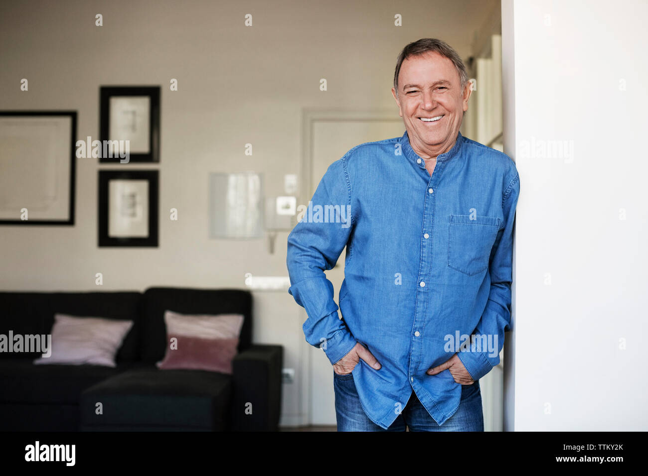 Portrait von Happy älterer Mann, der mit den Händen in den Taschen zu Hause Stockfoto