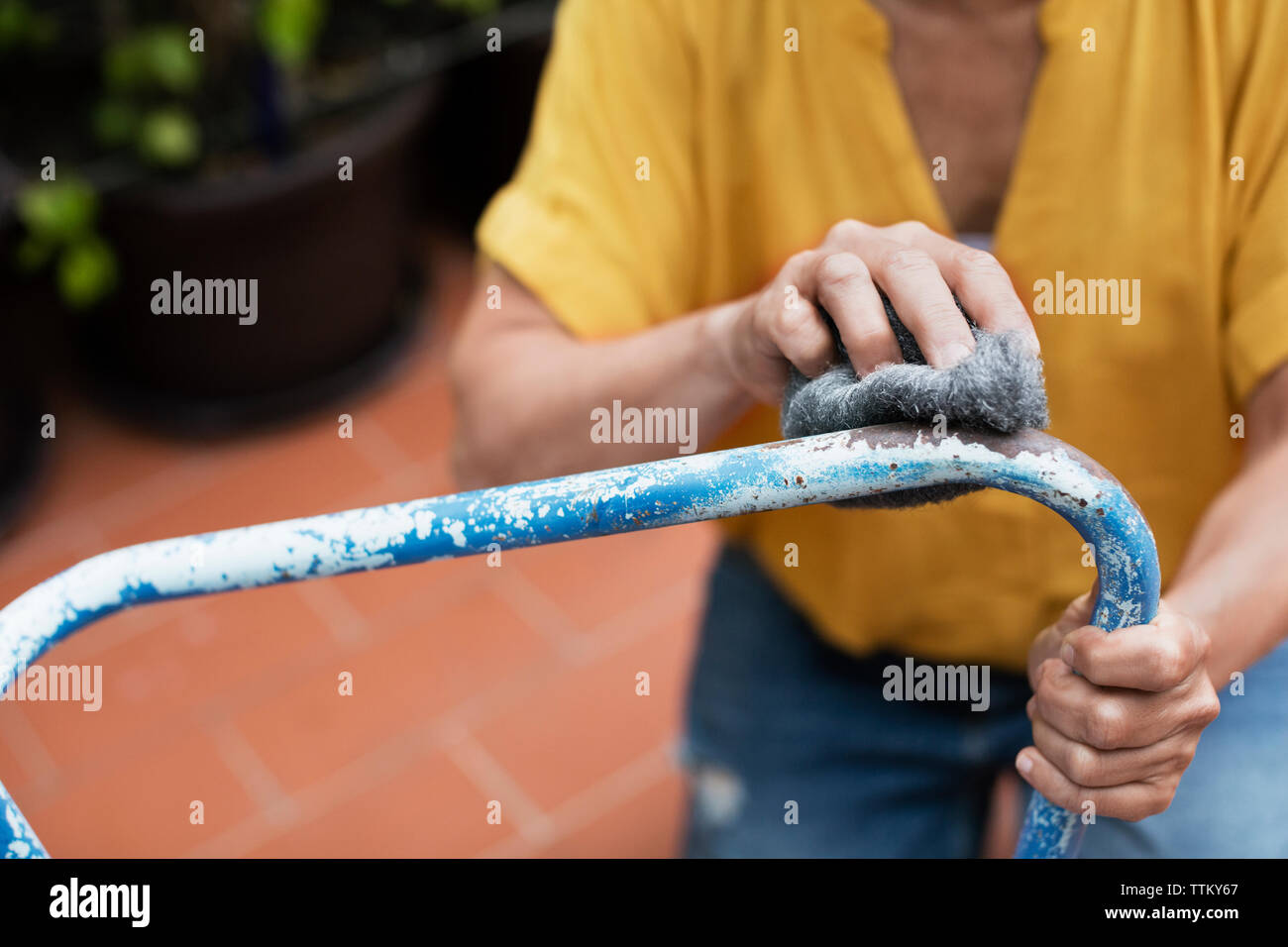 Mittelteil der Frau schrubben Stuhl mit Stahlwolle im Hof Stockfoto