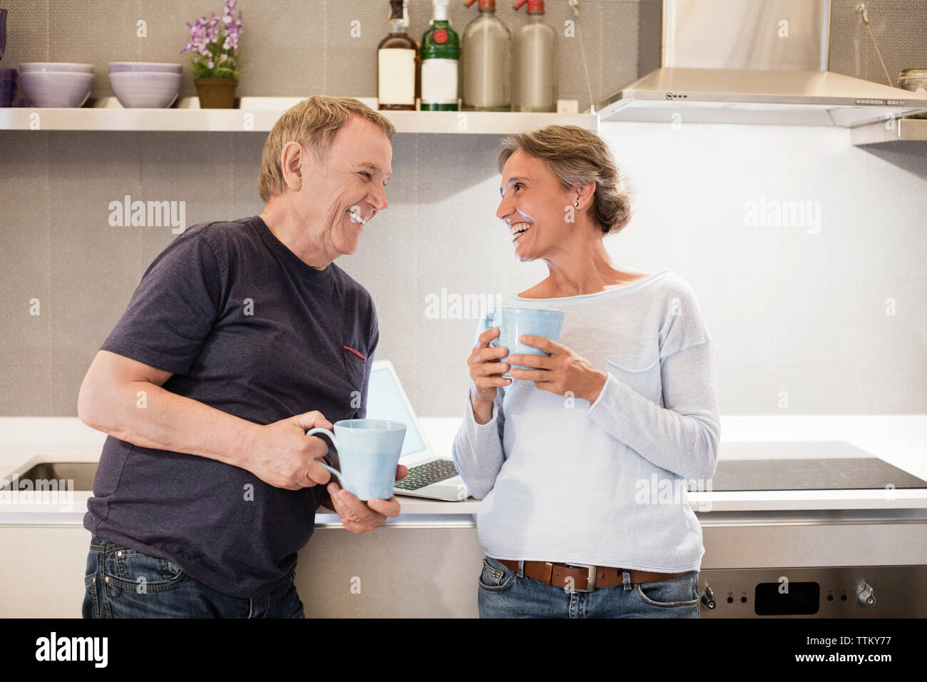 Freundliche ältere Ehepaar miteinander reden halten Kaffeetassen in der Küche Stockfoto