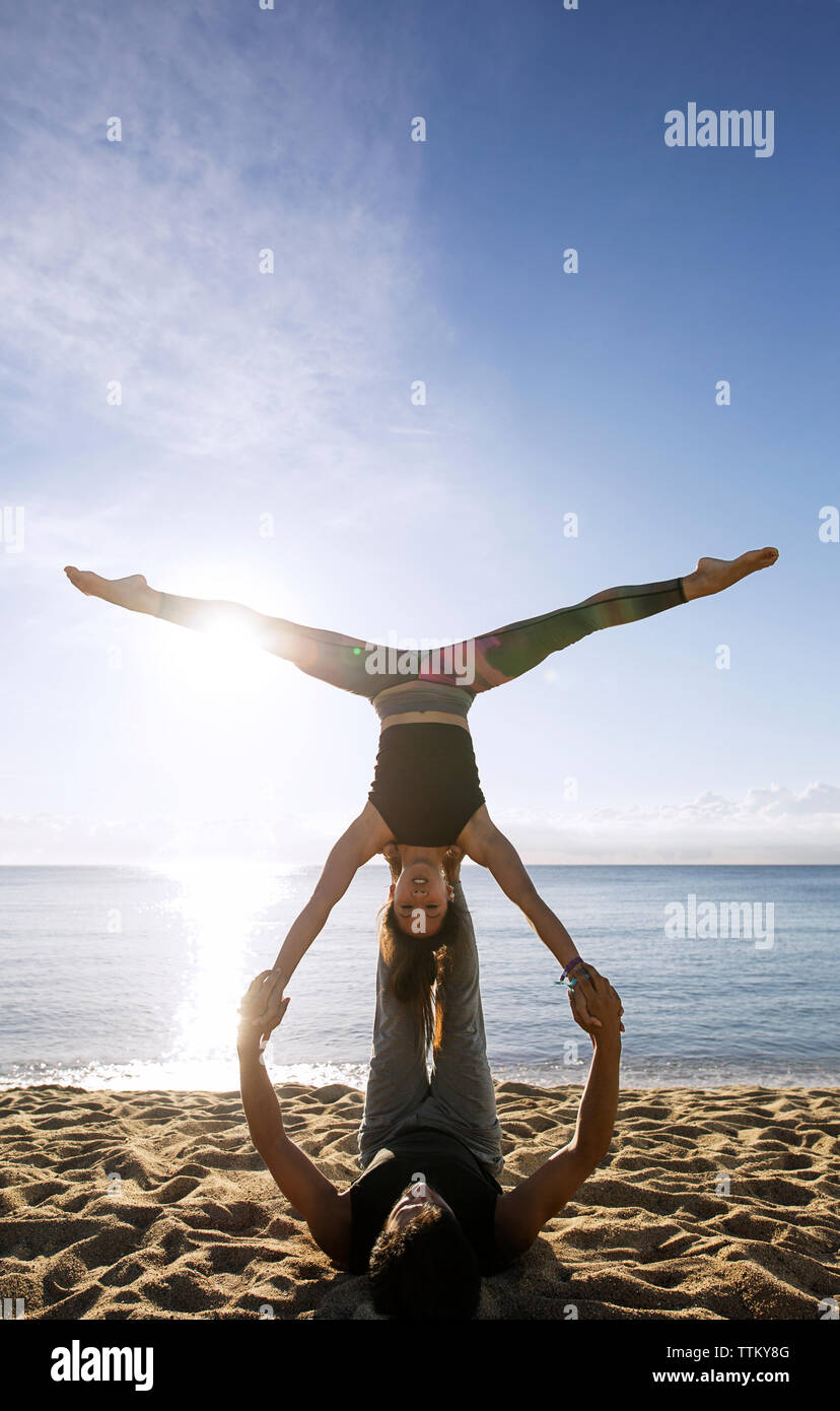 Bestimmt multi-ethnischen Paar Yoga am Ufer gegen Sky Stockfoto