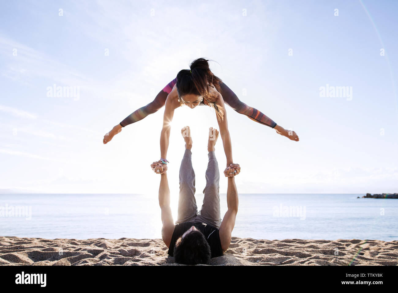 Mann anheben Frau beim Yoga am Strand im Sommer Stockfoto