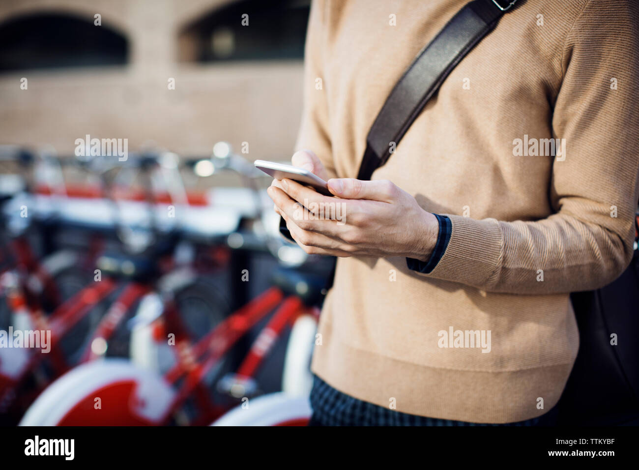 Mittelteil der über Handy und Fahrrad parken Bahnhof stehende Mann Stockfoto