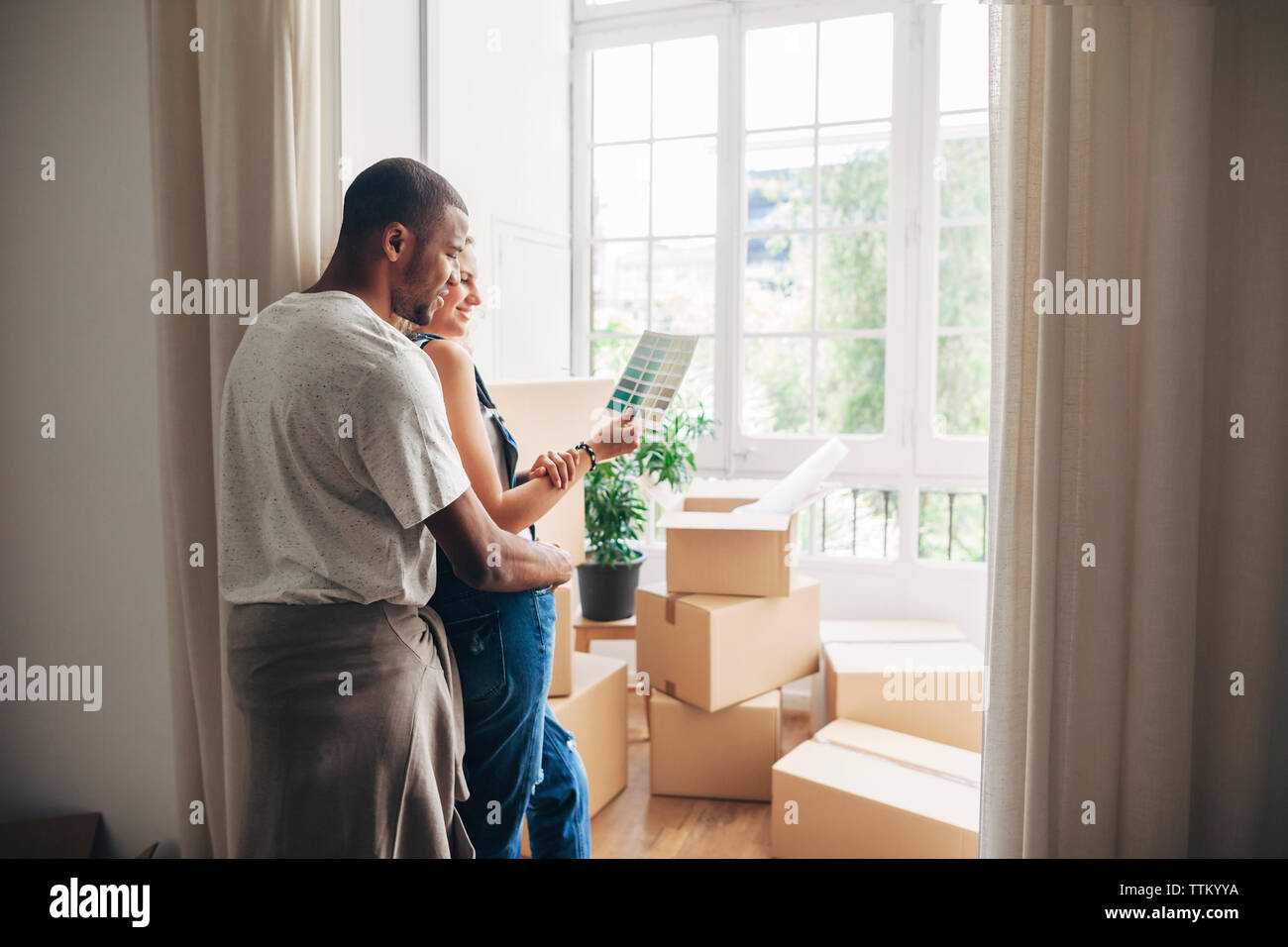 Auf der Suche nach Farbmuster, während durch die Wand im neuen Zuhause schiefen Stockfoto