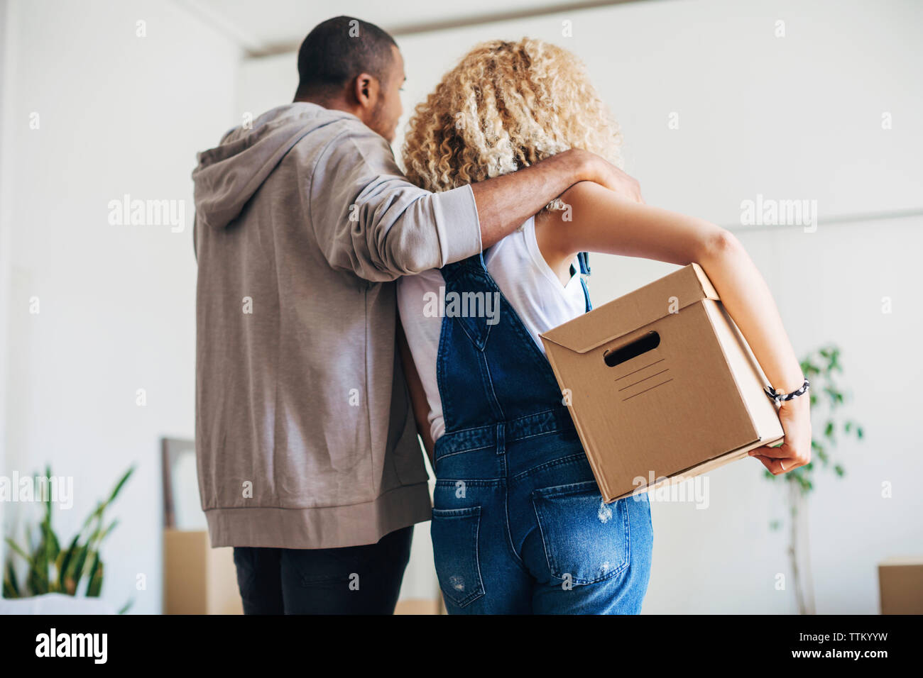 Ansicht der Rückseite Frau, die box mit Ehemann im neuen Haus Stockfoto