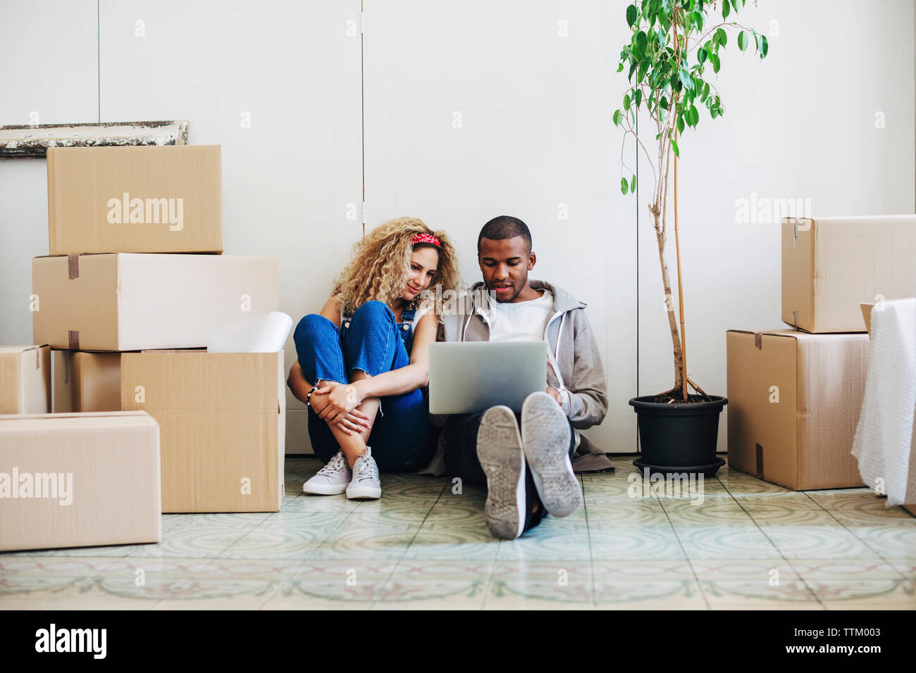 Paar mit Laptop Computer, während auf dem Boden am neuen Haus sitzt Stockfoto