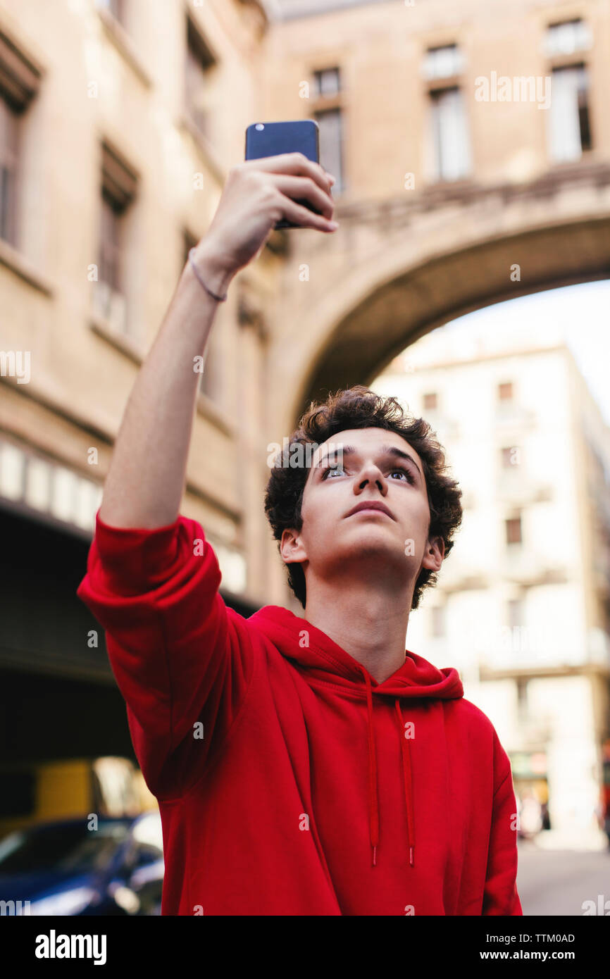 Low Angle View der Teenager fotografieren mit Smart Phone beim Stehen in der Stadt Stockfoto