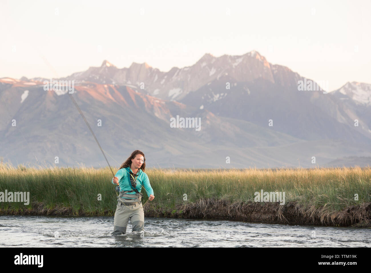 Junge Frau Fliegenfischen in Owens River gegen Berge Stockfoto