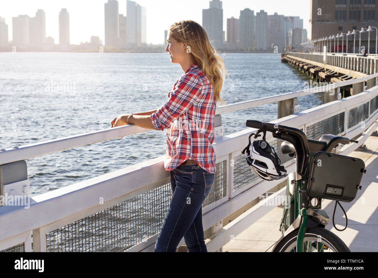 Frau mit Fahrrad auf Brücke am Fluss in der Stadt Stockfoto