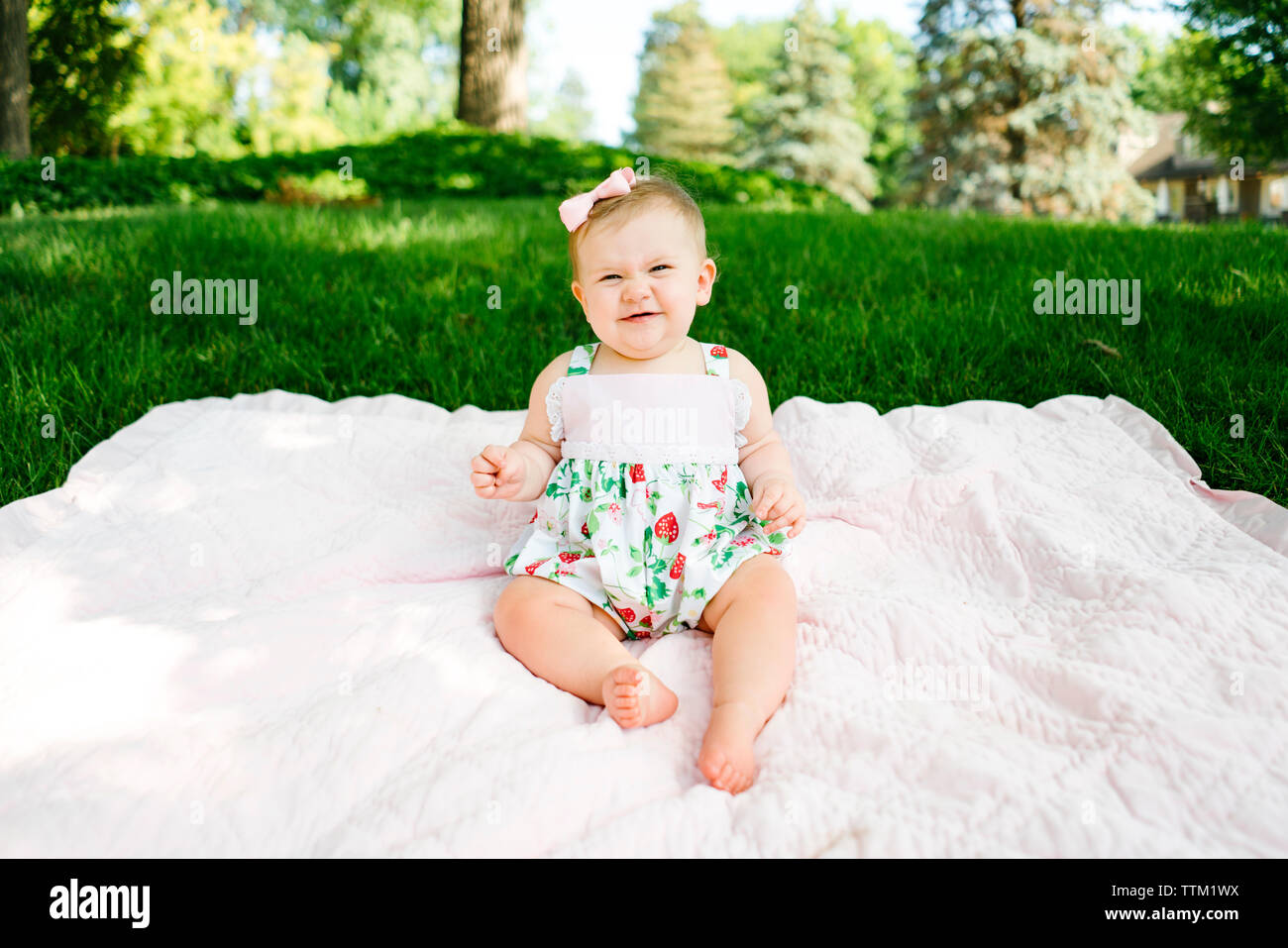 Ein Baby lacht, während auf einer Decke Sitzen Stockfoto