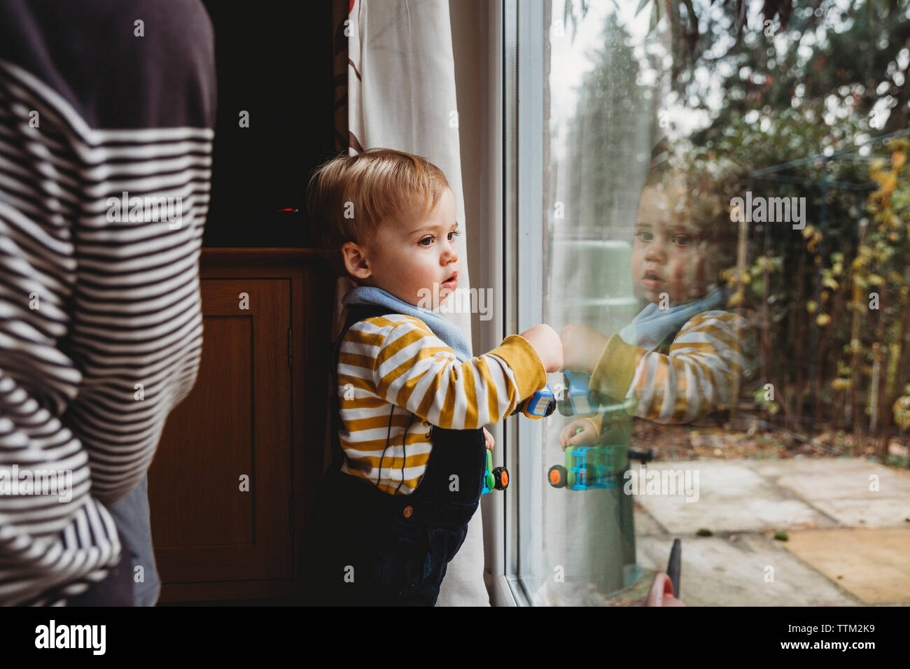 Cute Sohn gesucht durch das Fenster durch die Mutter zu Hause Stockfoto