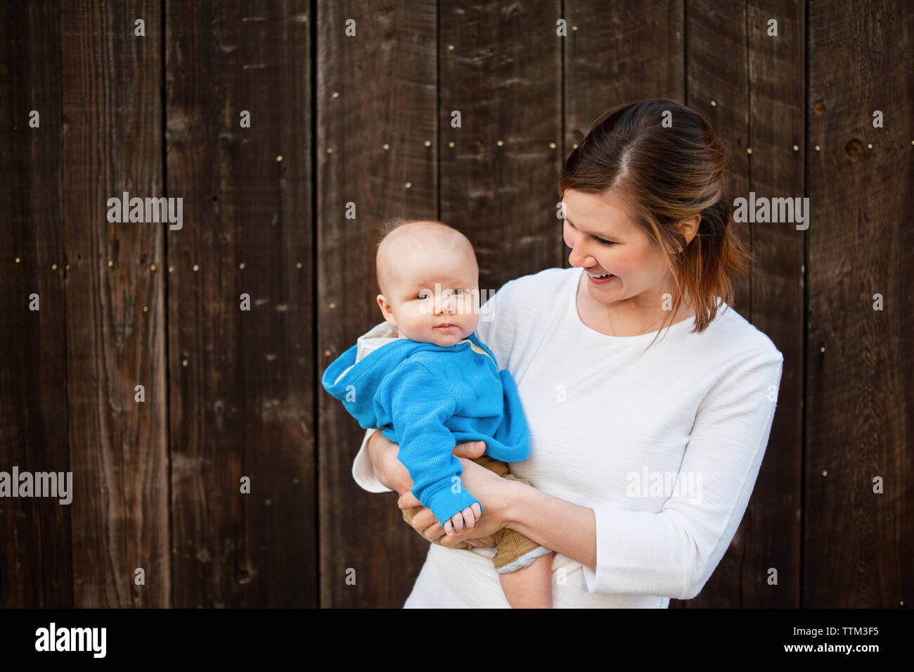 Glückliche Frau, die Jungen gegen die Holzwand Stockfoto