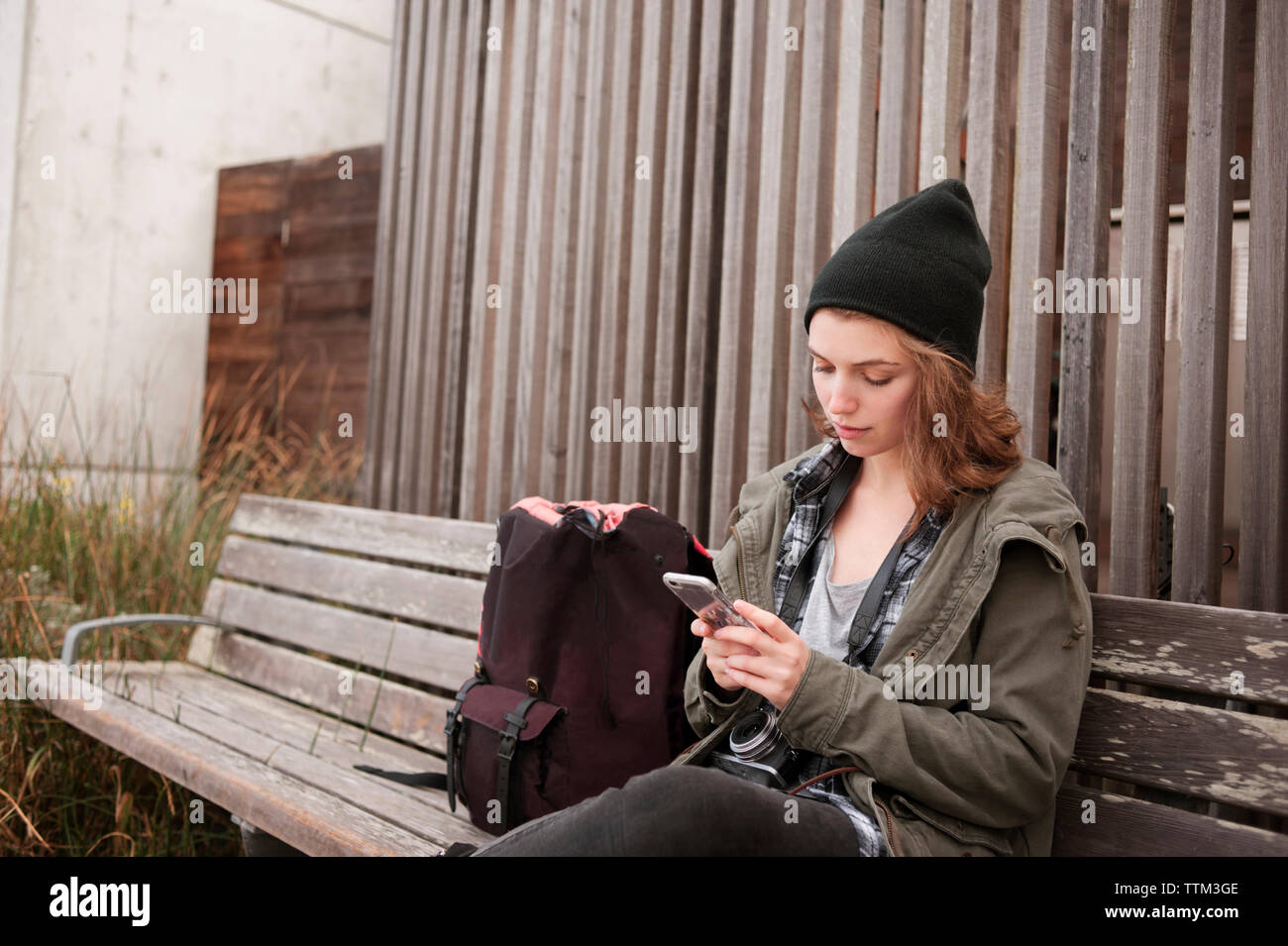 Junge Frau mit Smart Phone beim Sitzen auf der Werkbank Stockfoto