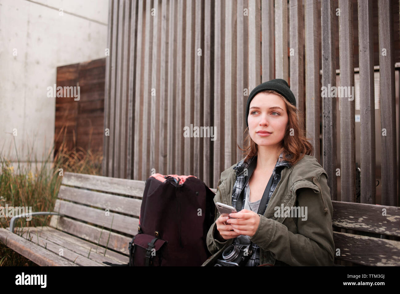 Nachdenklich weibliche Wanderer Holding smart phone beim Sitzen auf der Werkbank Stockfoto